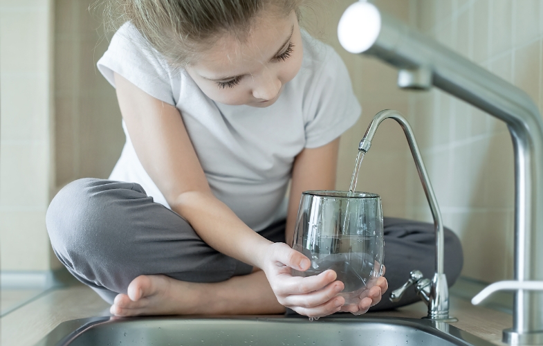 jente med vannglass tapper vann fra drikkevannskran