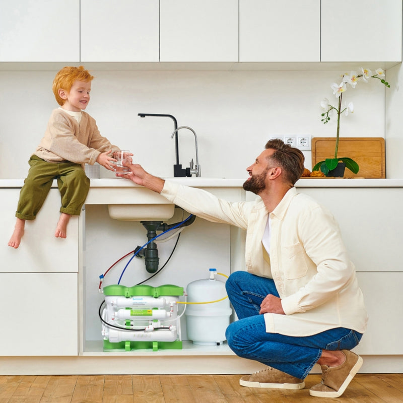 Ecosoft Pure Balance RO filter gutt som mottar et glass med renset vann fra mann