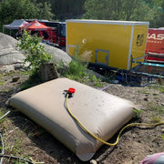 Vanntank i bruk på stevne for dusjformål; med hageslange for påfylling 